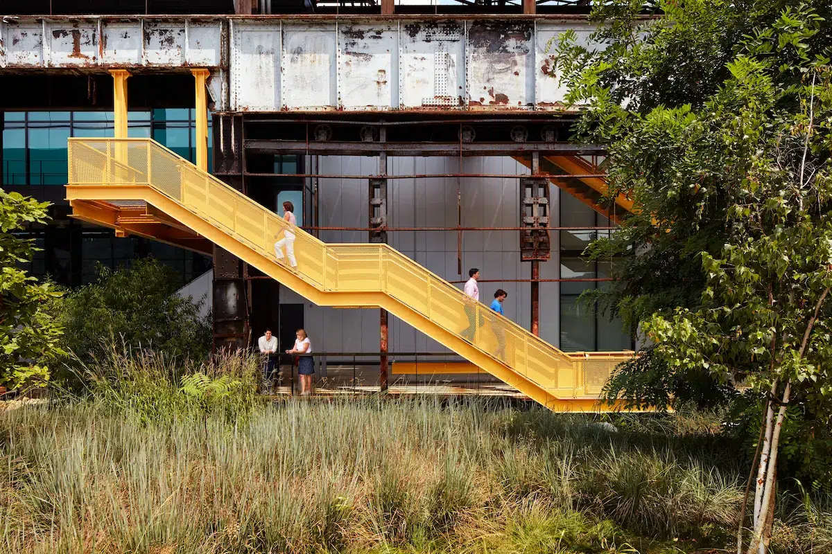 People descend a yellow staircase of an industrial building 