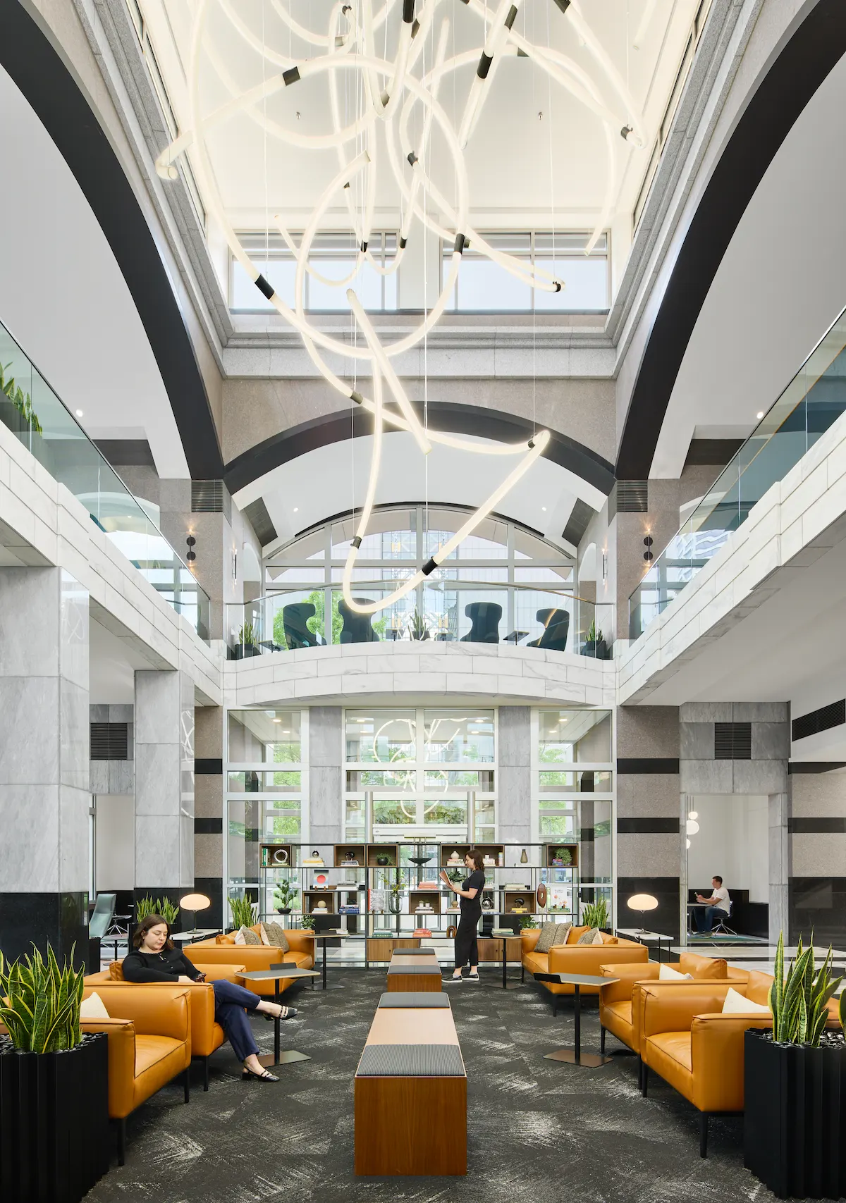 A bright office with yellow chairs natural light and a hanging statement light fixture