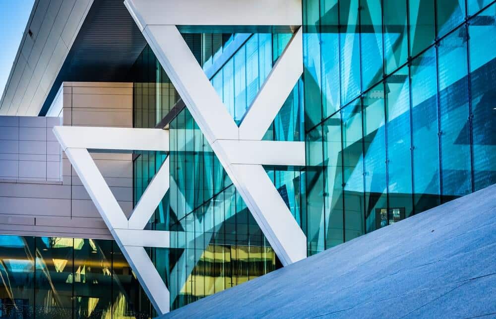 Modern building facade with large glass windows and intersecting white structural beams.