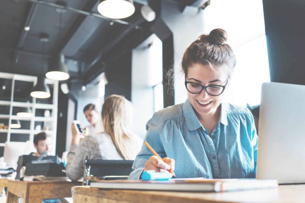 Young-woman-working-in-an-office-at-her-desk-and-taking-notes-on-CRE-data