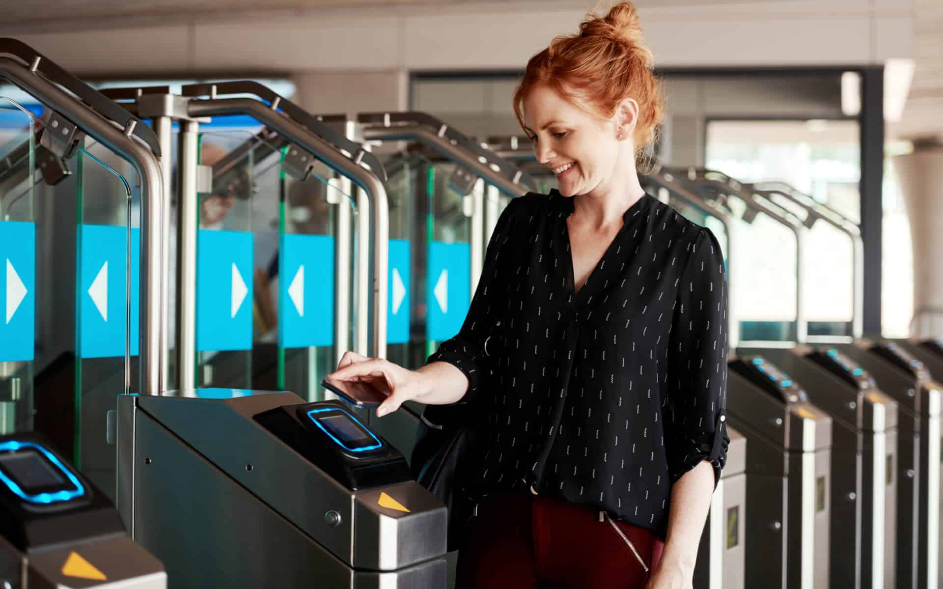 Woman uses a digital ticket at a modern turnstile in a transit station.
