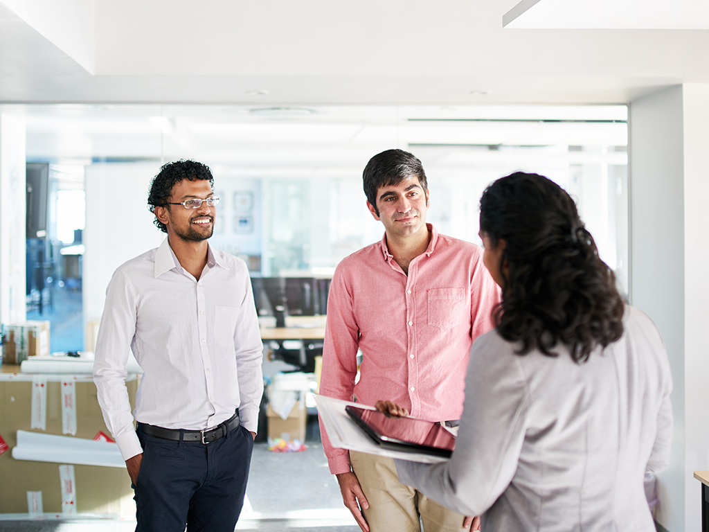 Businesswoman talking with colleagues while standing together in an office