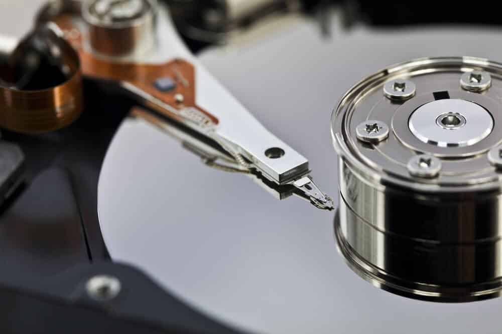 Close-up of an open hard disk drive showing the read/write arm and spinning platter.
