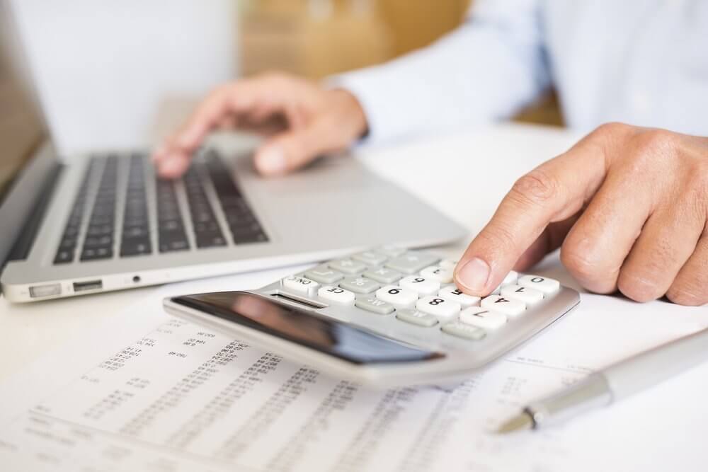 facility manager using a calculator and laptop