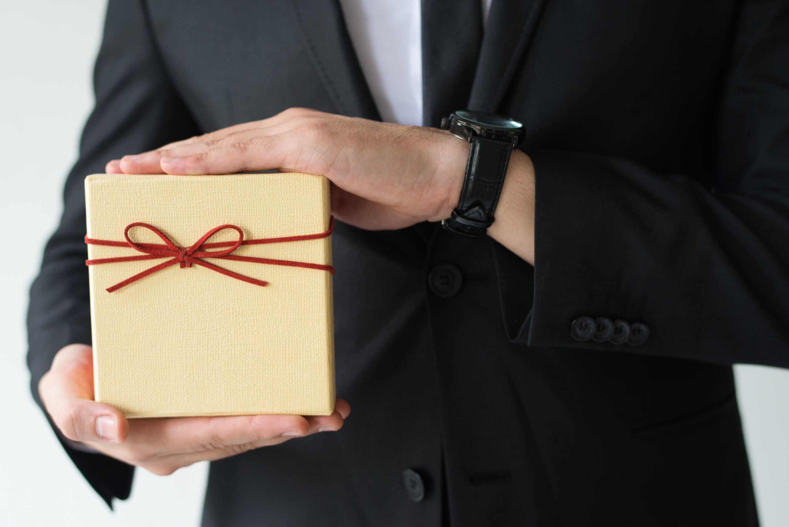man in a suit holding a gift box
