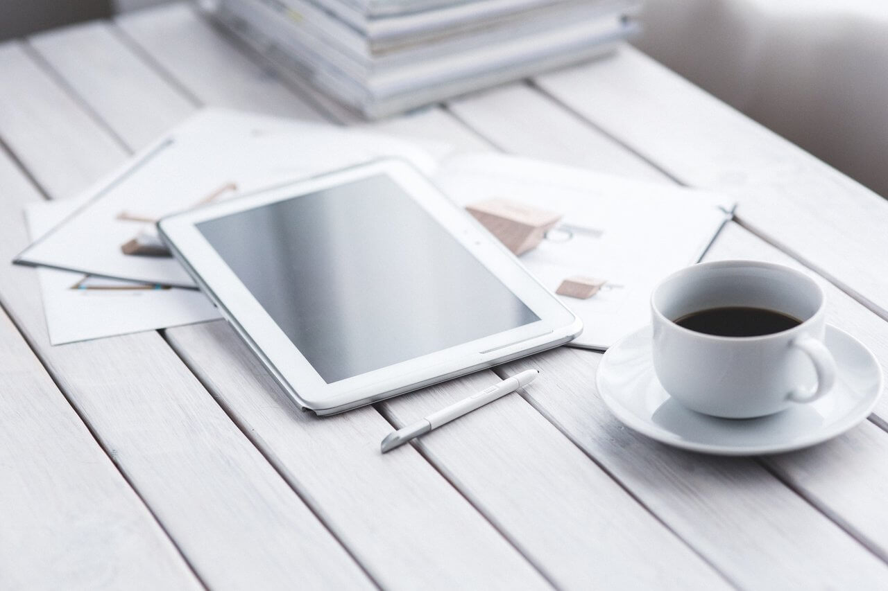 tablet, papers and coffee on desk