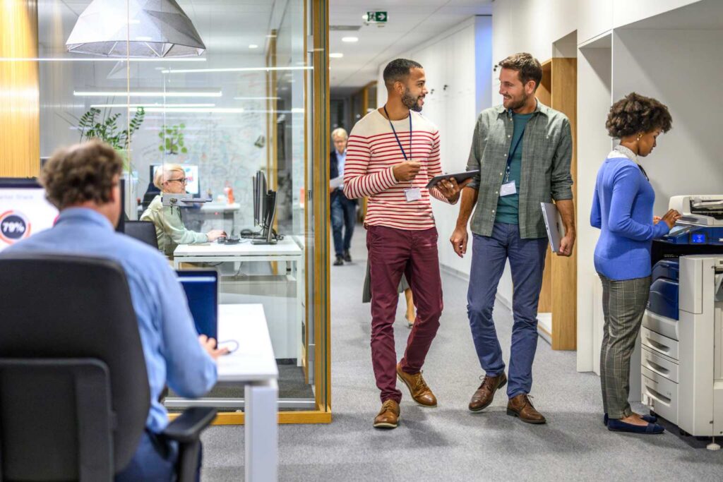 Coworkers chatting and walking in office corridor