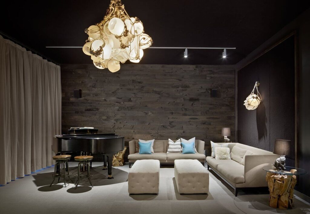 Modern living room with dark walls, beige sofas, a black grand piano, and unique pendant lights.