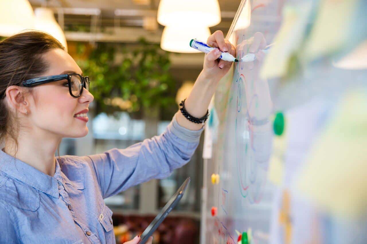 Girl Writes at Whiteboard Smiling