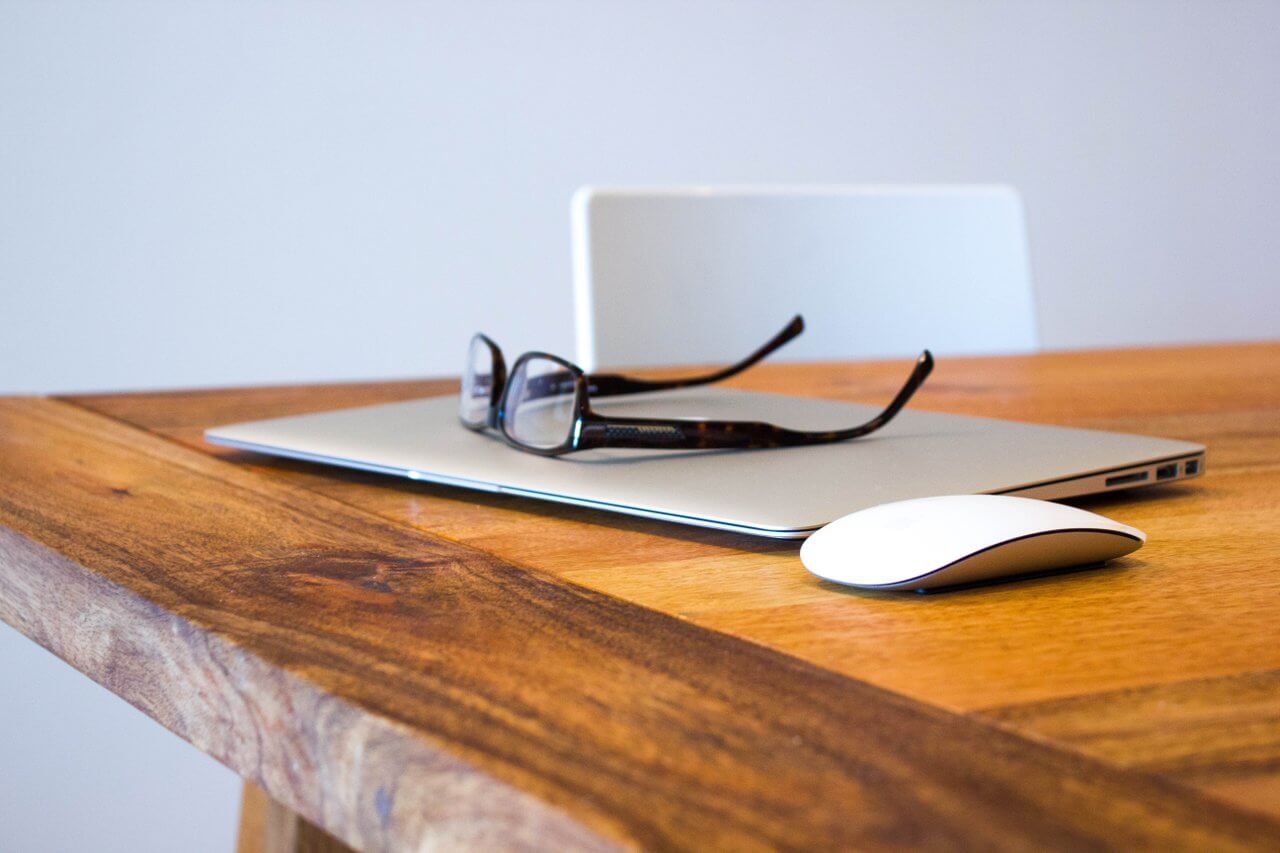 laptop, mouse and glasses on an office desk