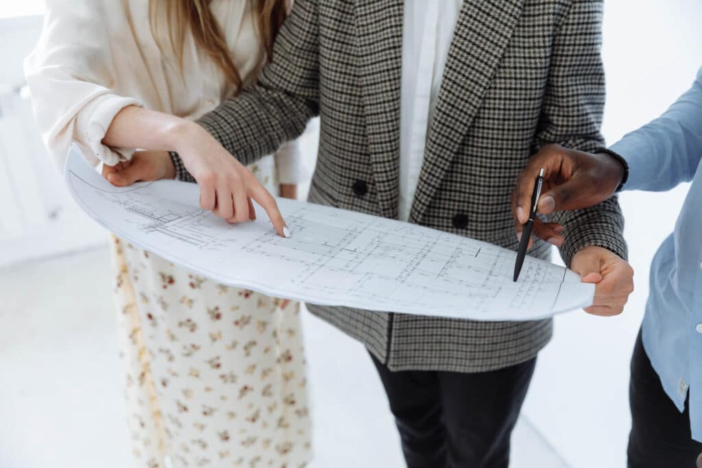 Three people reviewing architectural blueprints together.