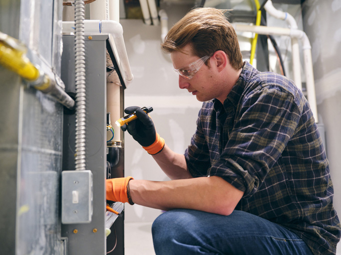 A repairman working inside an office, repairing a furnace.