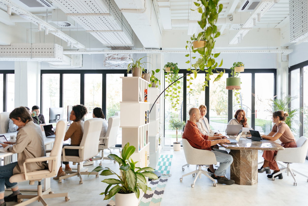 A bright and vibrant co-working office featuring diverse professionals collaborating, immersed in an open and green workplace.