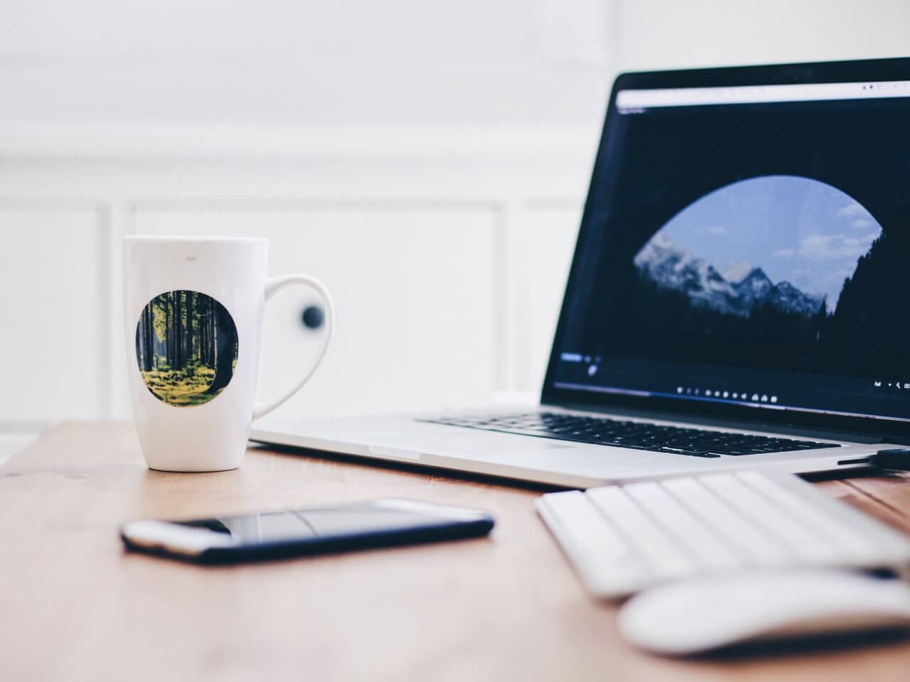 laptop, phone and cup of tea on desk