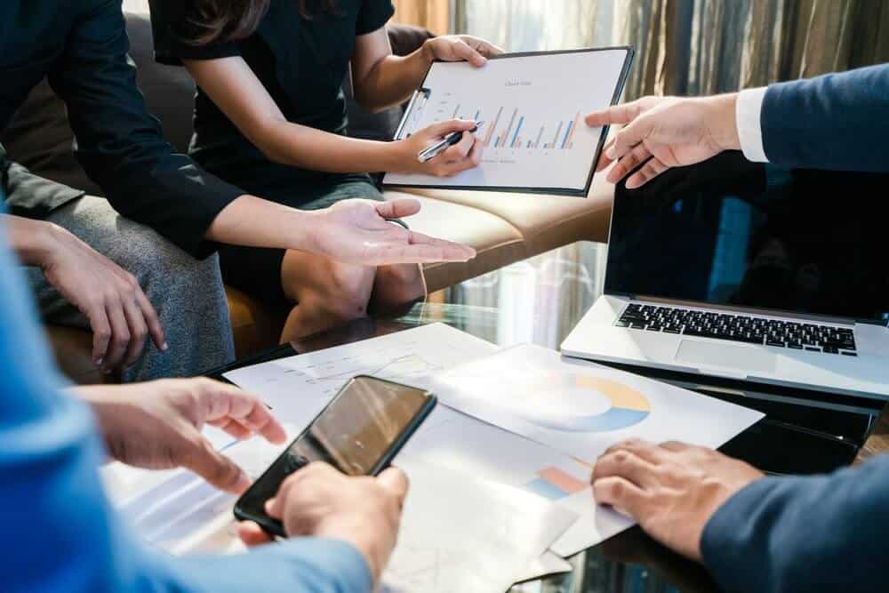 team of office workers reviewing reports with tech integrations team of office workers reviewing reports with tech integrations