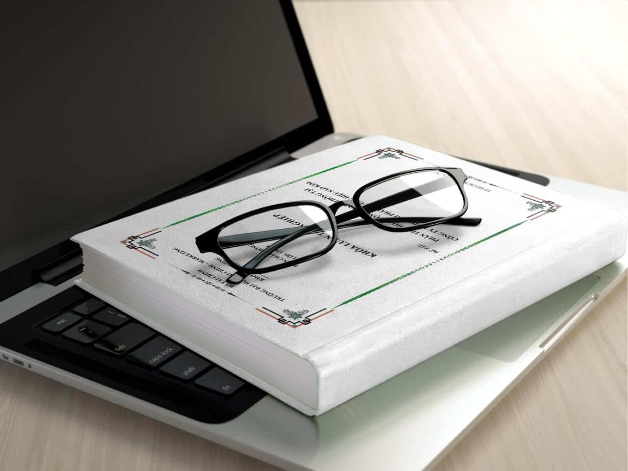 glasses, book and laptop on table