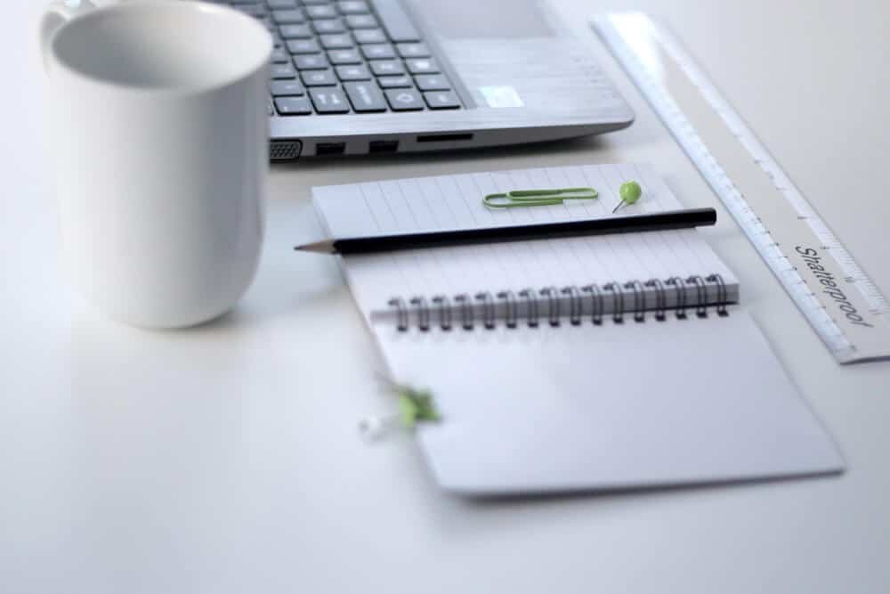 laptop, pencil, notebook and cup on desk