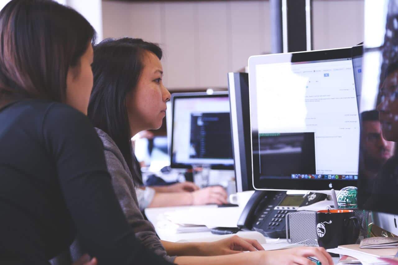 two employees looking at a computer two employees looking at a computer