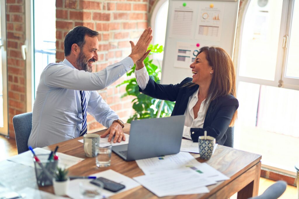 a man and a woman in the office doing a high-five