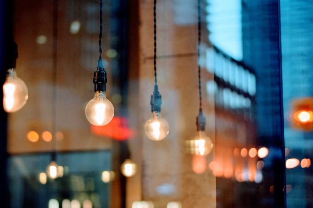 Hanging light bulbs with city building reflections in a window.