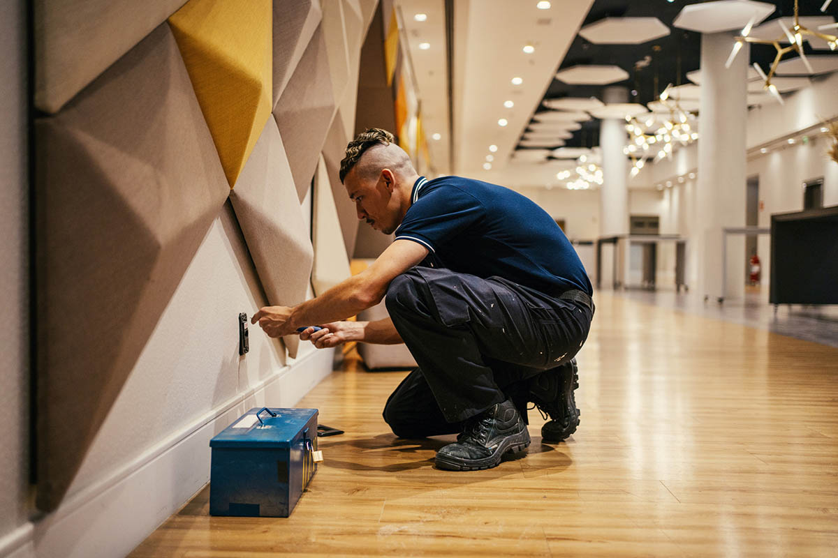 Maintenance worker working on wall outlet.