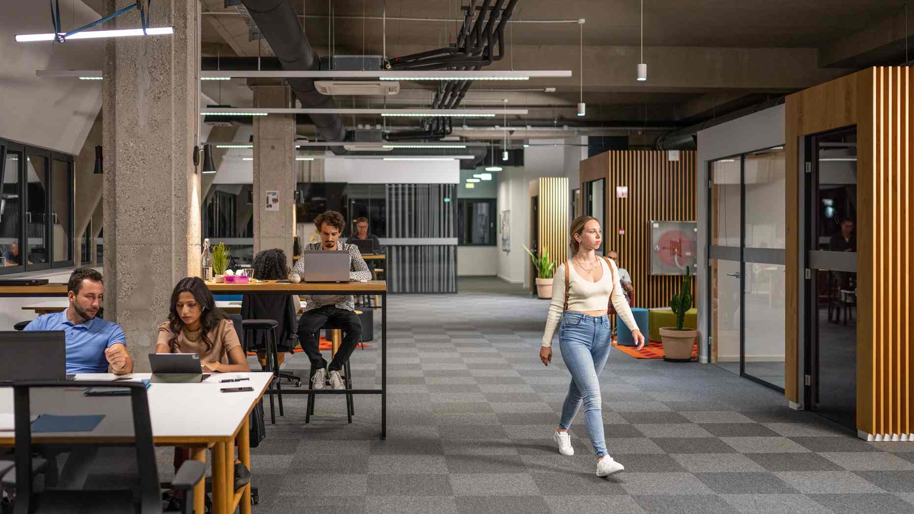 A woman in jeans walks through a modern office.
