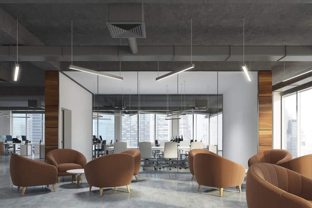 Modern office with brown seating area, large windows, and a glass-walled conference room with a city view.