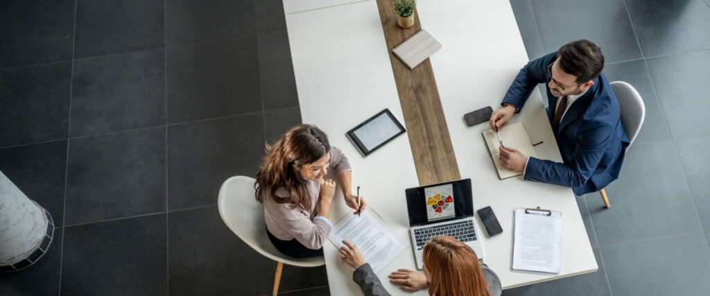 Three business professionals reviewing workplace platform vs point solution options during an office strategy meeting