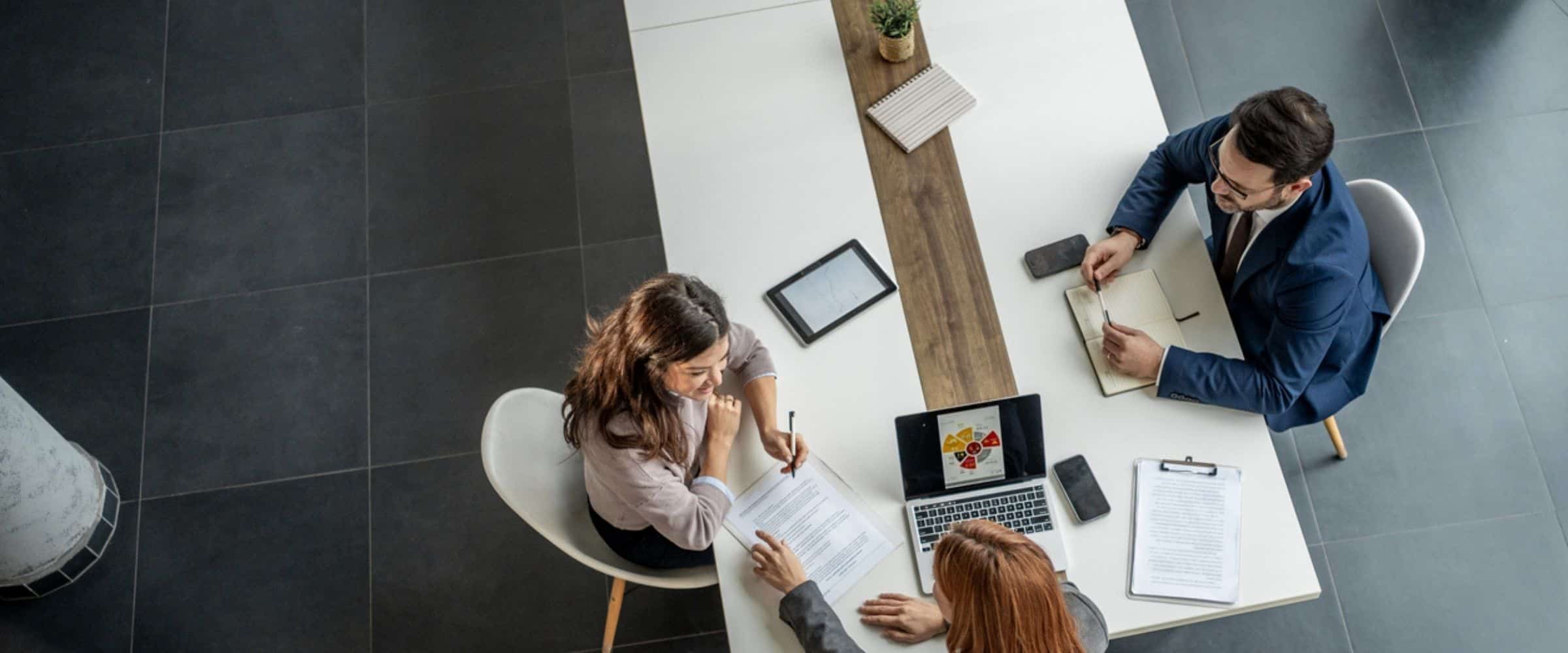 Three business professionals reviewing workplace platform vs point solution options during an office strategy meeting