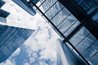 Upward view of modern glass skyscrapers against a cloudy sky.