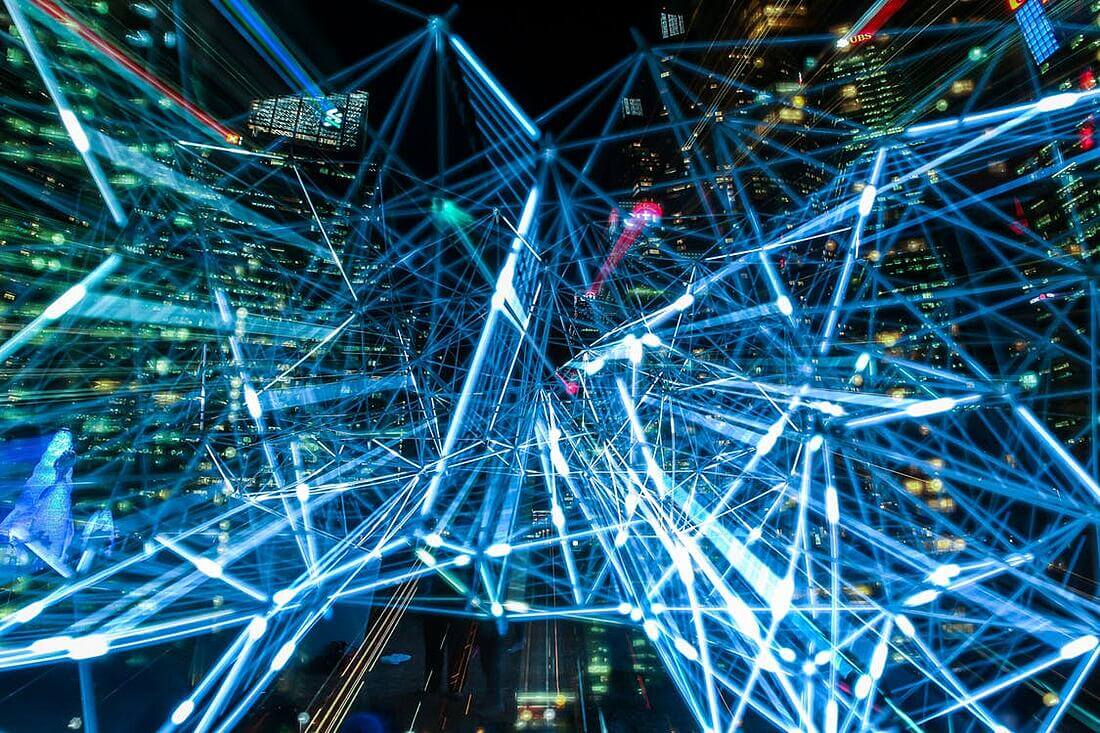 Abstract network of glowing blue lines against a blurred cityscape at night.